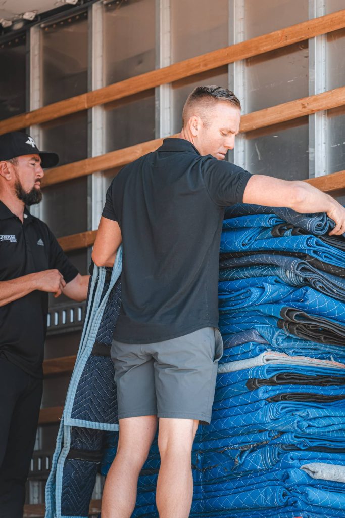 Workers loading blue moving blankets into truck
