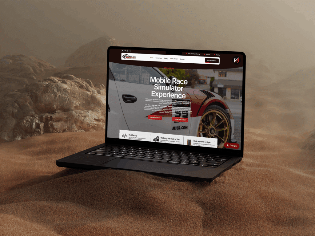 Laptop displaying racing simulator website on sandy surface